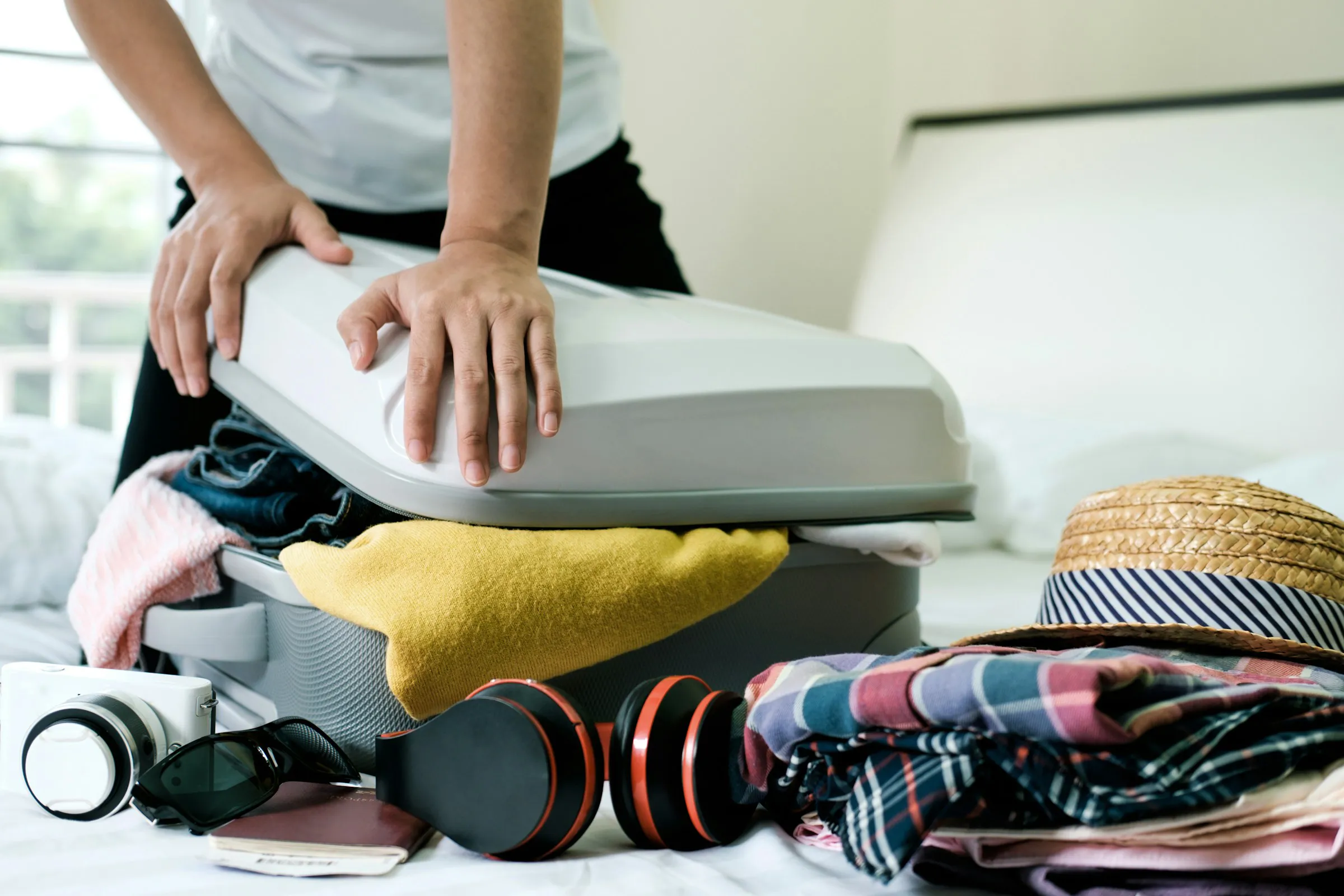 Un homme essayant de fermer son bagage cabine trop plein